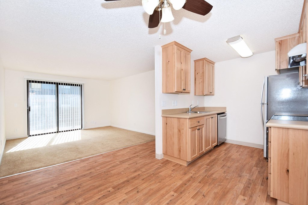 an empty kitchen and living room with wood flooring and a window