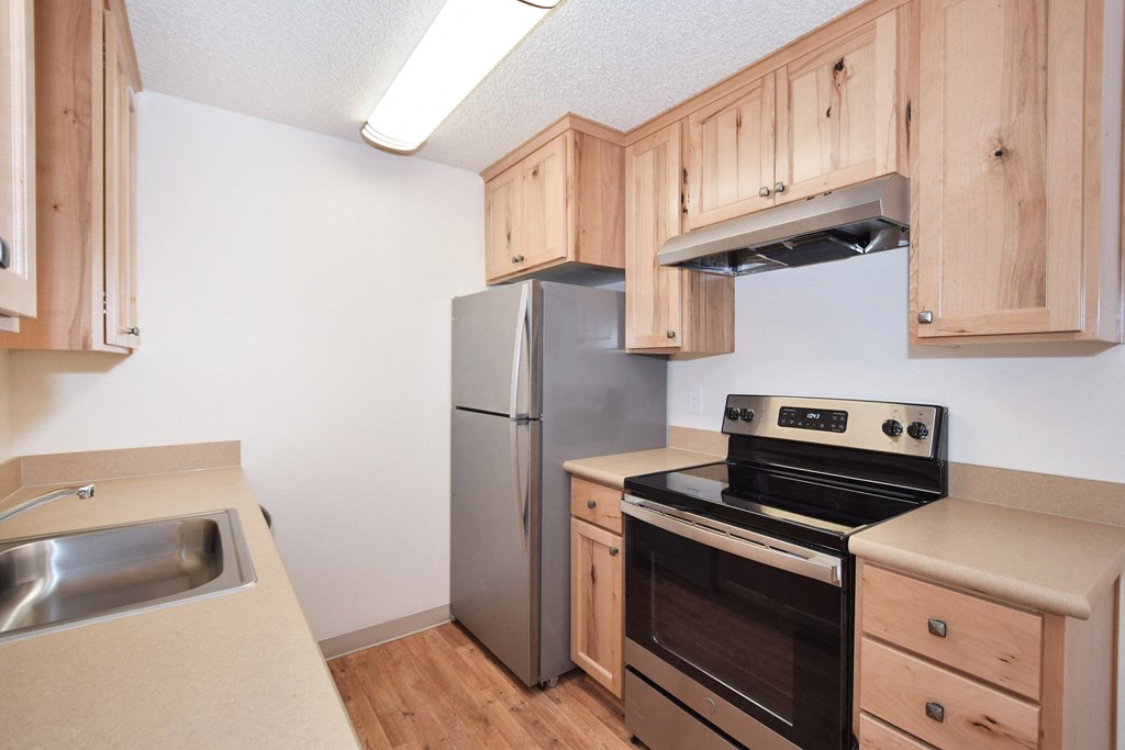an empty kitchen with wooden cabinets and stainless steel appliances