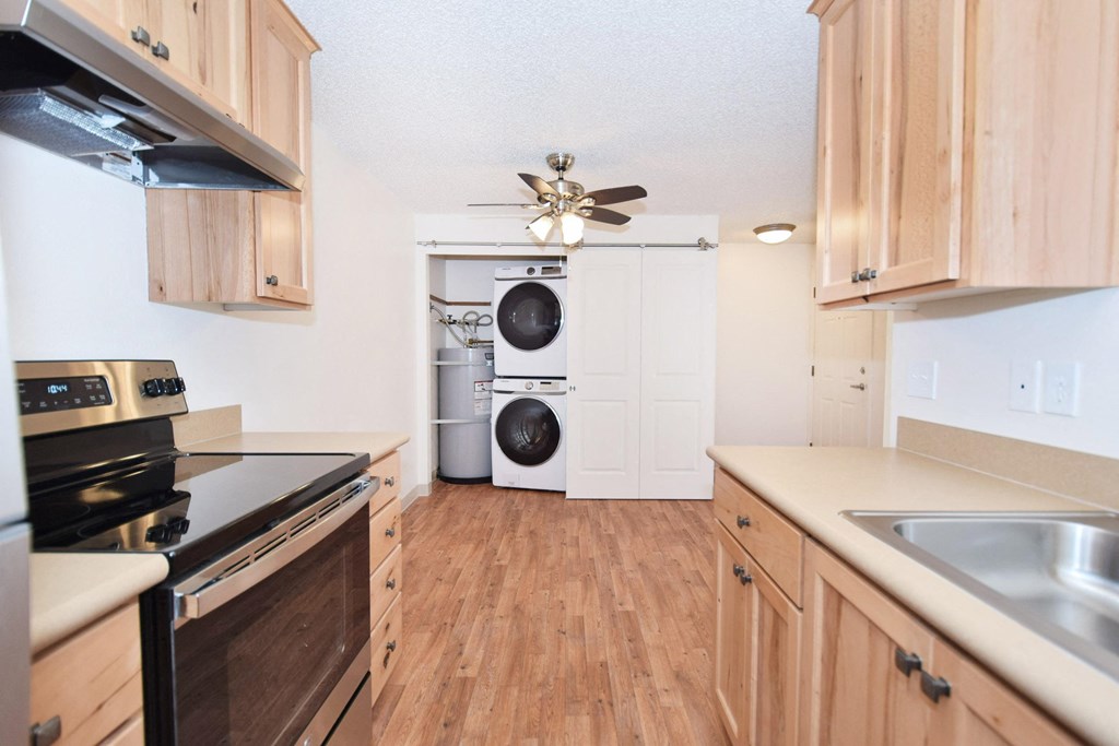 a kitchen with wooden cabinets and a washer and dryer in it