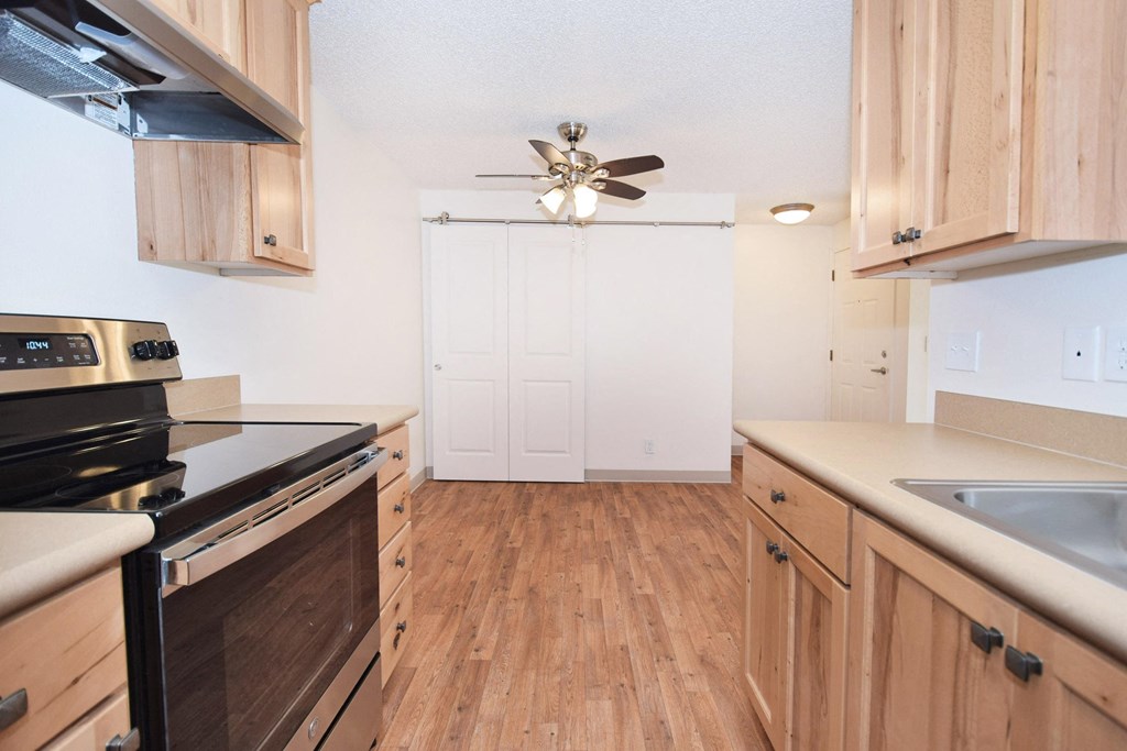 an empty kitchen with wood flooring and a ceiling fan