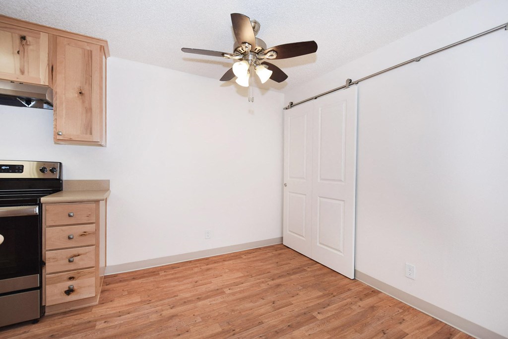 an empty kitchen with a ceiling fan and a stove