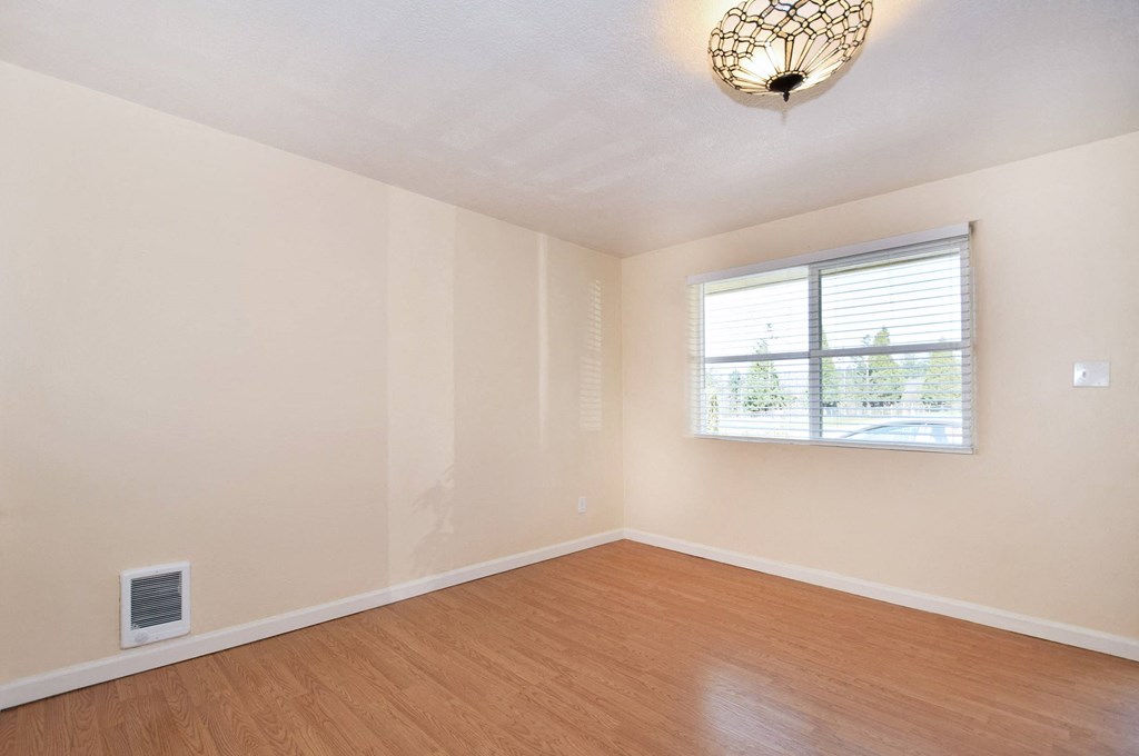 an empty living room with wood floors and a window