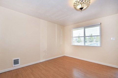an empty living room with wood floors and a window