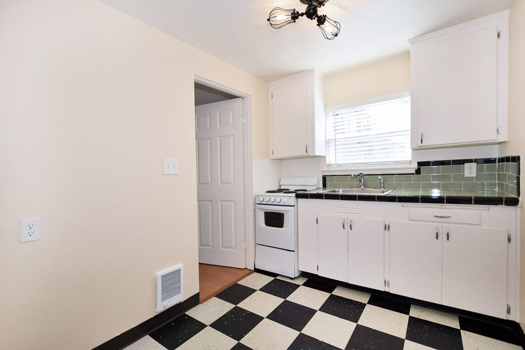a kitchen with black and white checkered floor and white appliances