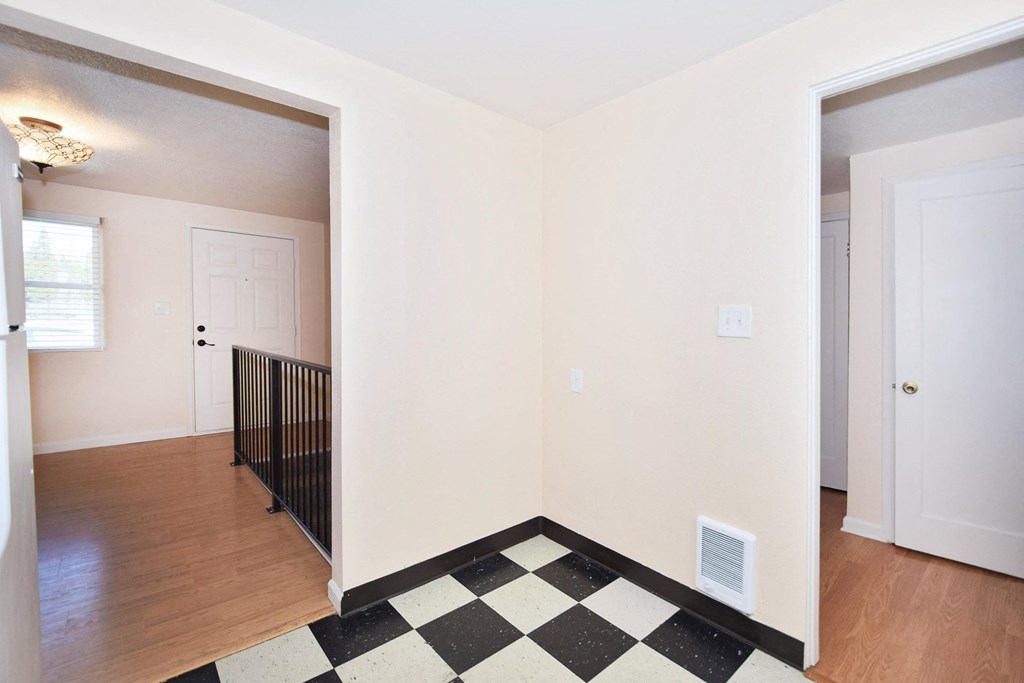 a renovated living room with a checkered floor and a door to a hallway