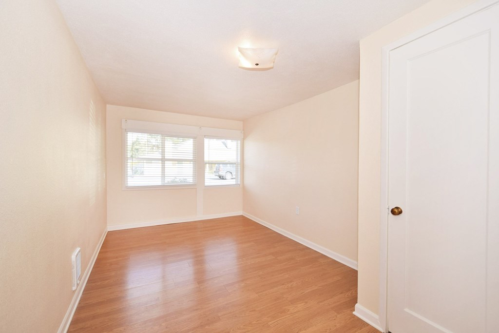 an empty living room with wood floors and a window