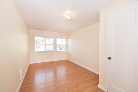 an empty living room with wood floors and a window