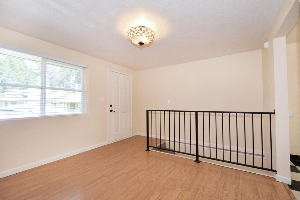 the upstairs loft of a home with a railing and a window