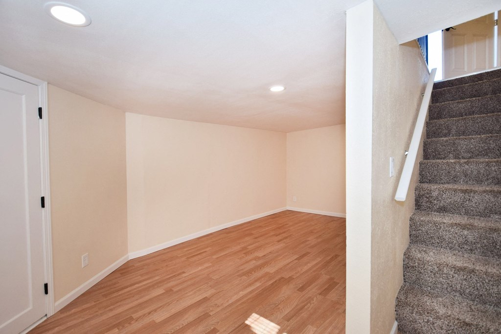 an empty living room with wood flooring and stairs