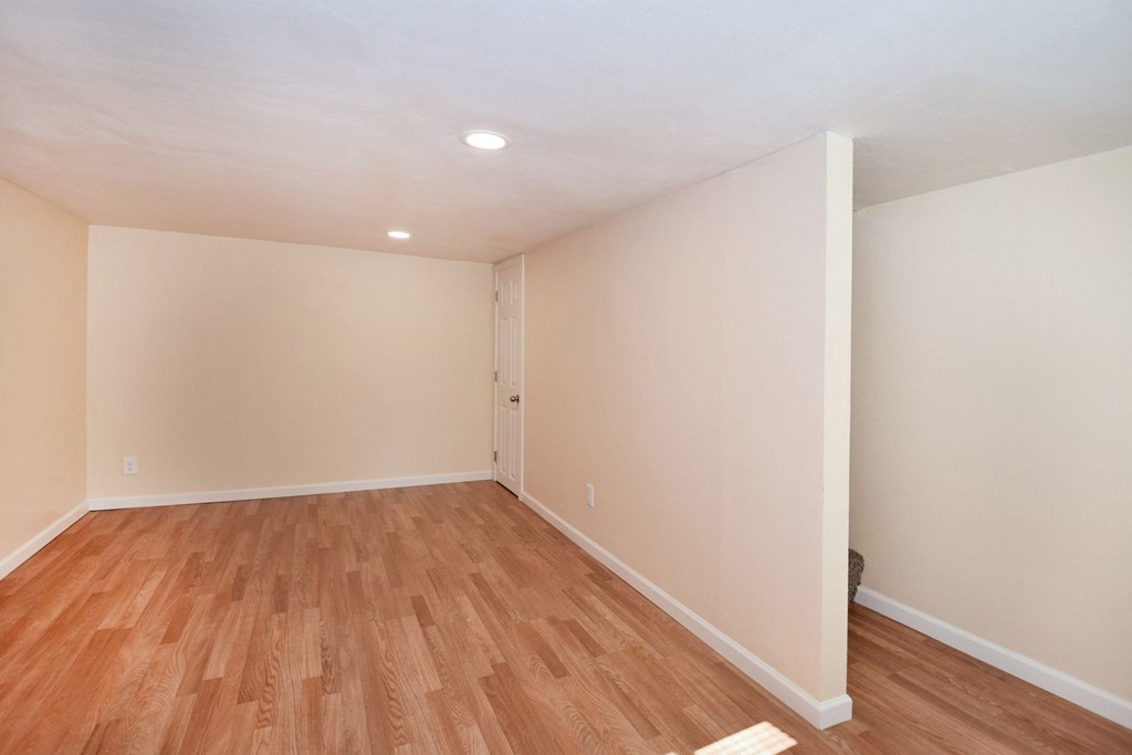 an empty living room with wood flooring and white walls