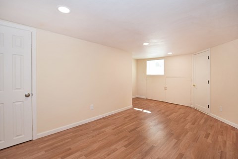 an empty living room with wood flooring and white walls