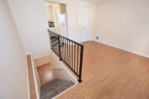 the view from the top of the stairs into the kitchen and living room of a