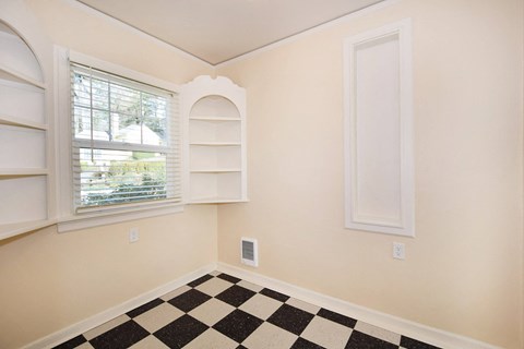 a room with a checkered floor and a window and white shelves