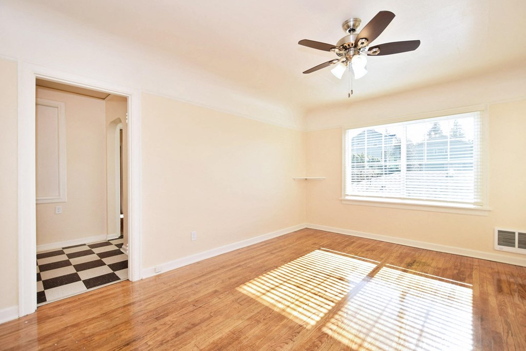 an empty living room with a ceiling fan and a window