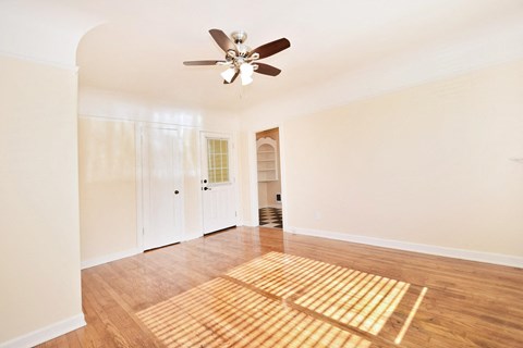 an empty living room with a ceiling fan