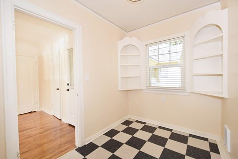 a renovated living room with a checkered floor and white shelves