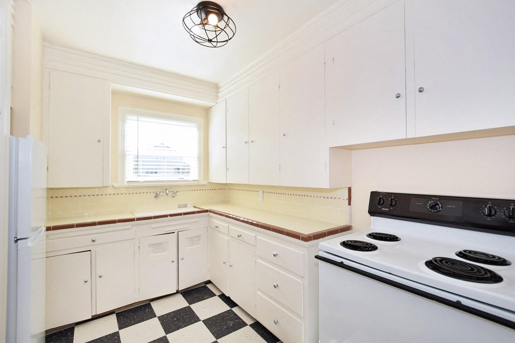 a kitchen with white appliances and black and white checkered floor