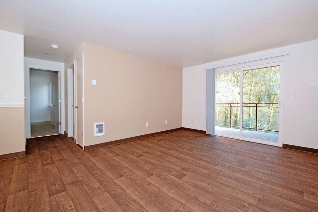 an empty living room with hardwood floors and a large window