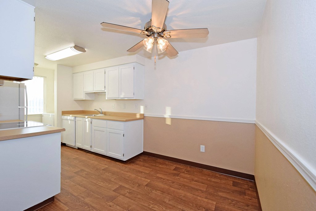 an empty kitchen with white cabinets and a ceiling fan