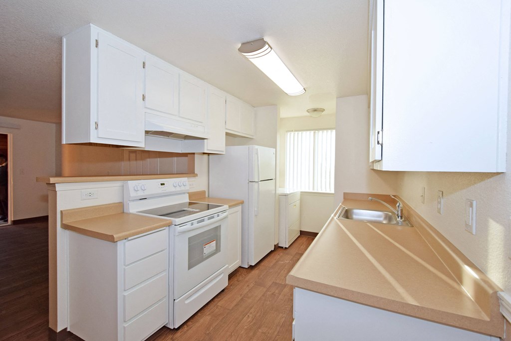 an empty kitchen with white appliances and white cabinets