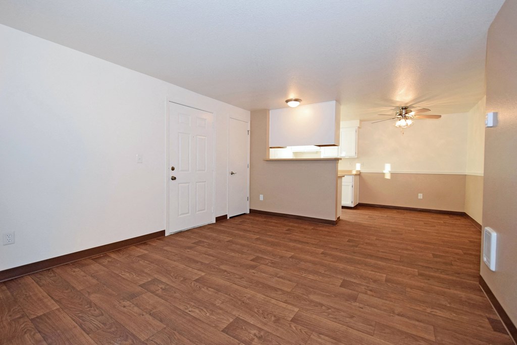 an empty living room with wood flooring and a ceiling fan