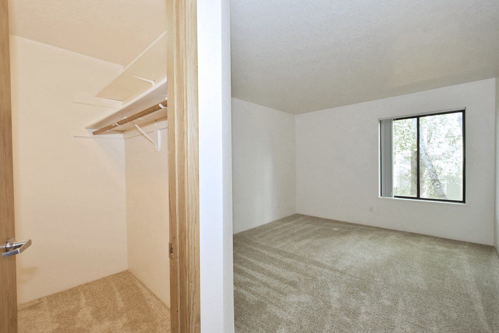 an empty bedroom with a window and a closet