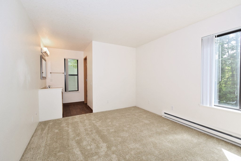 a bedroom with a large window and a carpeted floor