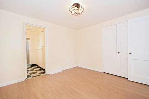 an empty living room with wood flooring and white doors