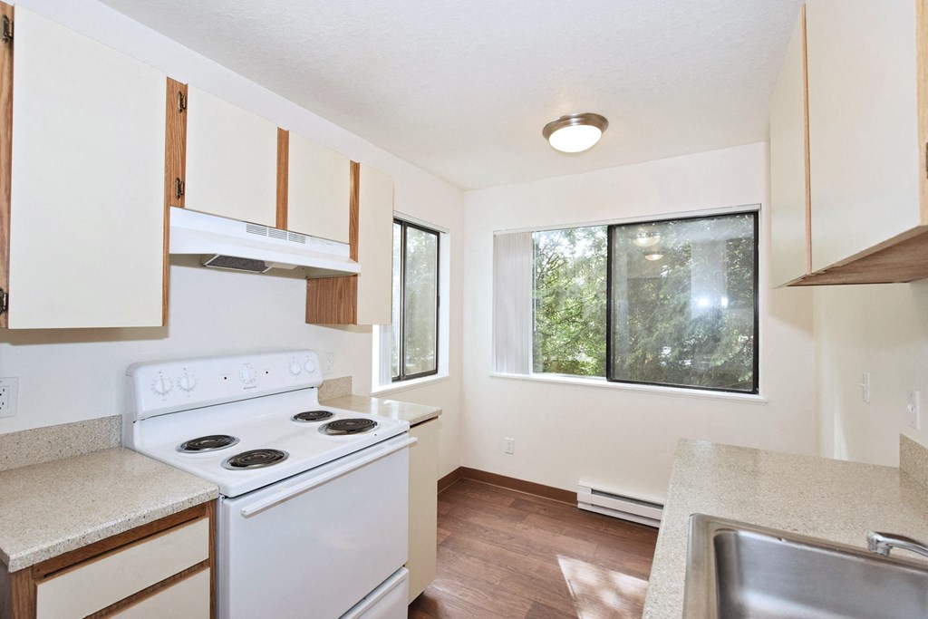 a kitchen with white appliances and a large window