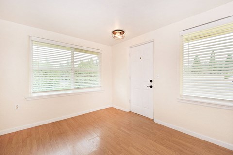 a bedroom with a door and two windows and a wood floor