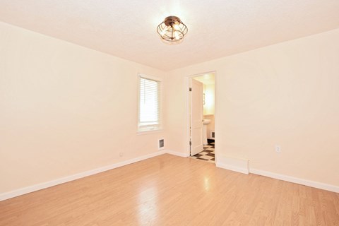 an empty living room with a hardwood floor and a window