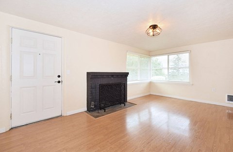 an empty living room with a fireplace and wooden floors