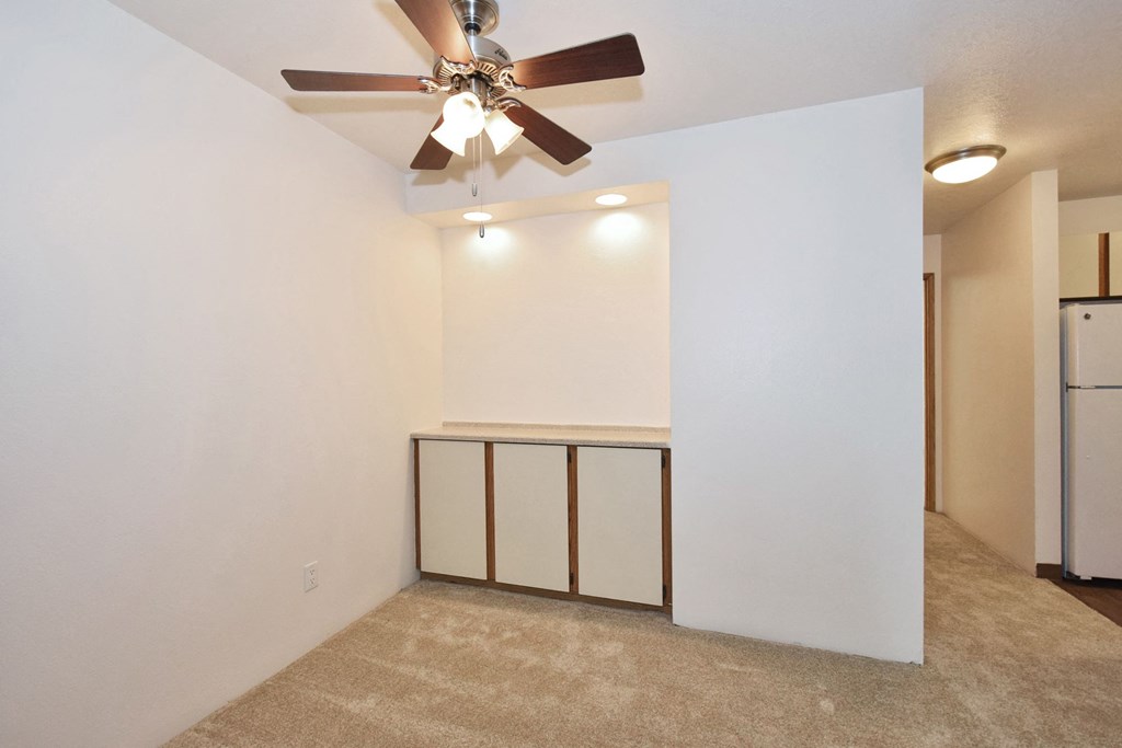 a living room with white walls and a ceiling fan