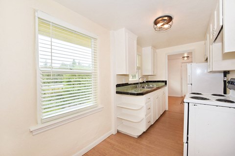a kitchen with white cabinets and a sink and a window