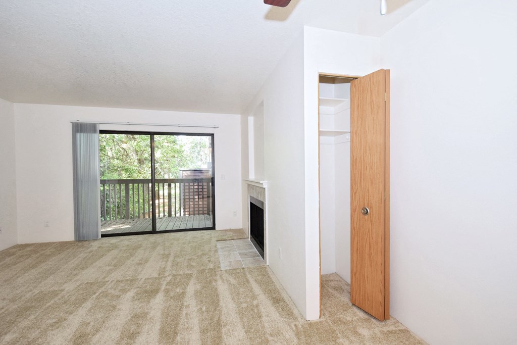 an empty living room with a sliding glass door leading to a balcony