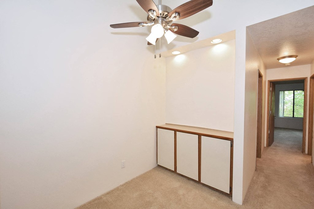 a bedroom with white walls and a ceiling fan