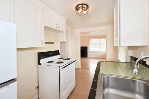 an empty kitchen with white appliances and a sink