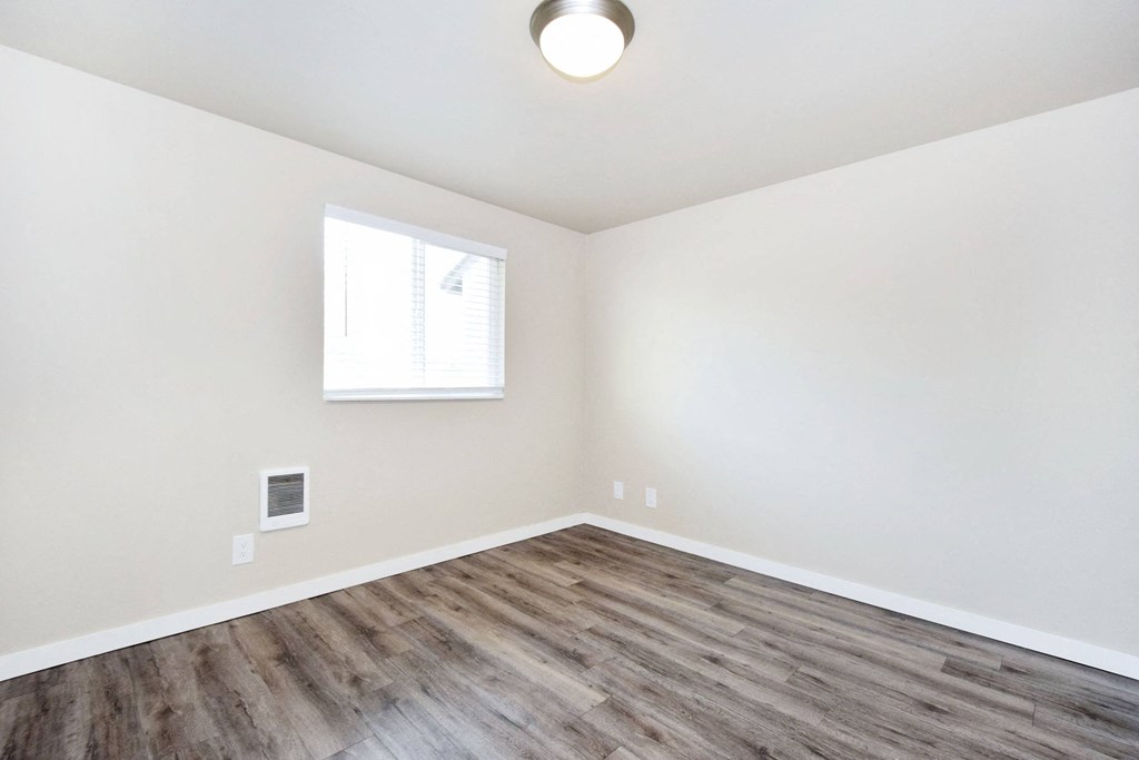 an empty living room with wood flooring and a window