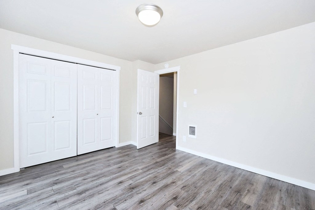 an empty living room with white walls and wood floors