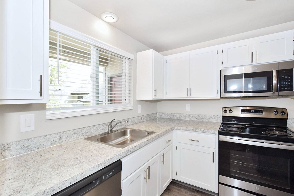 a kitchen with white cabinets and granite counter tops and black appliances