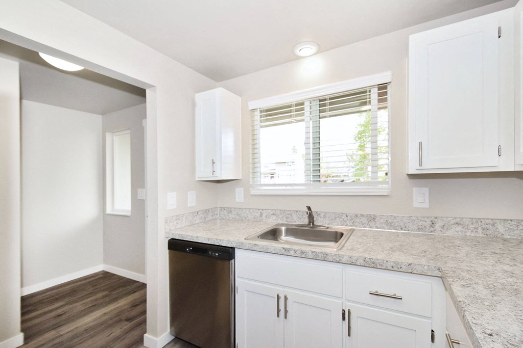 a kitchen with white cabinets and a sink and a window