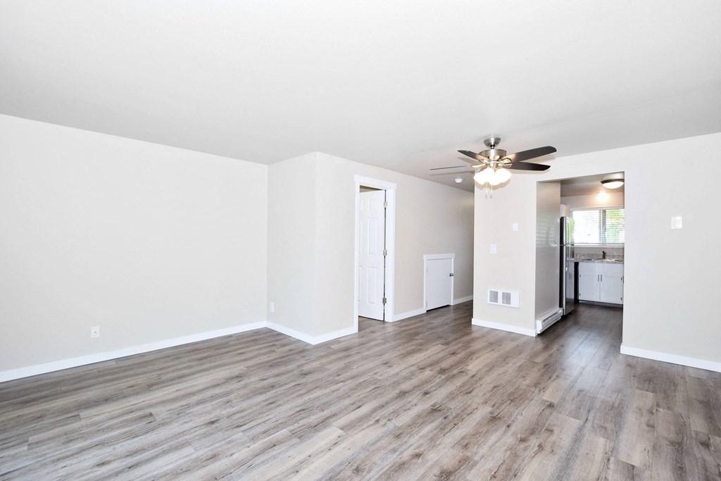 an empty living room with white walls and a ceiling fan