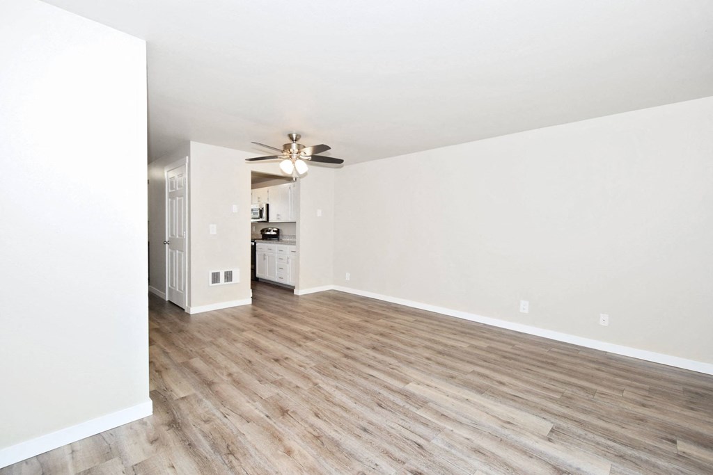 an empty living room with white walls and wood floors