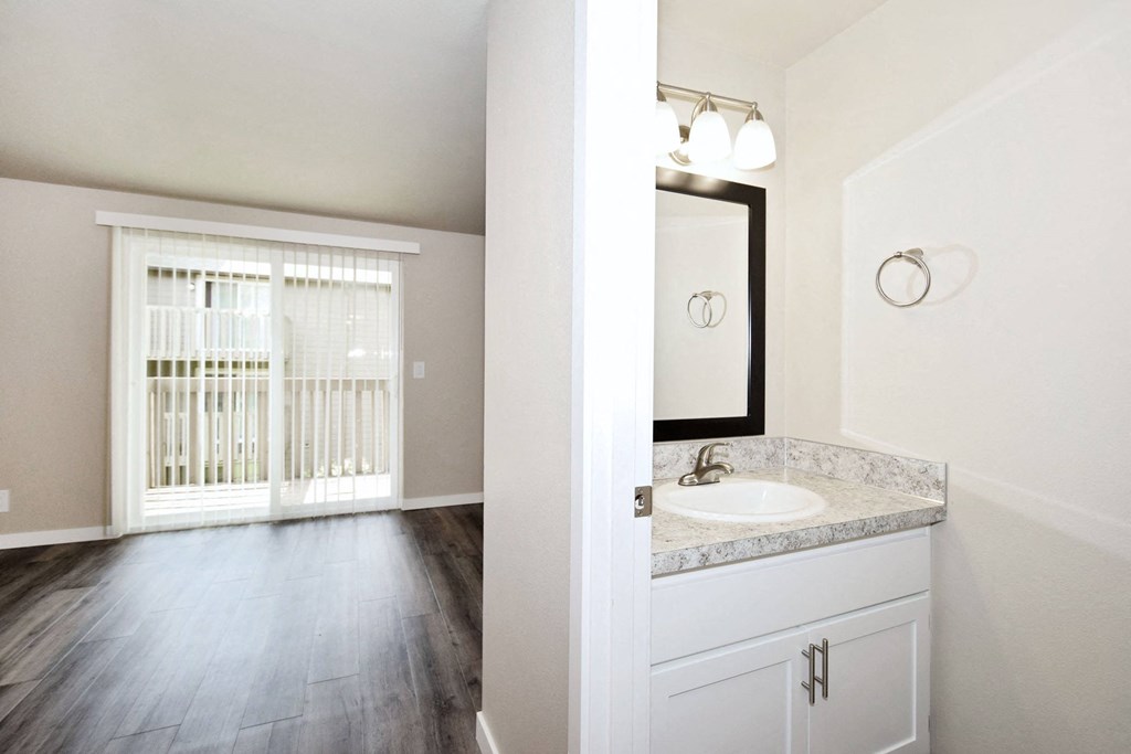 an empty bathroom with a window and a sink and mirror
