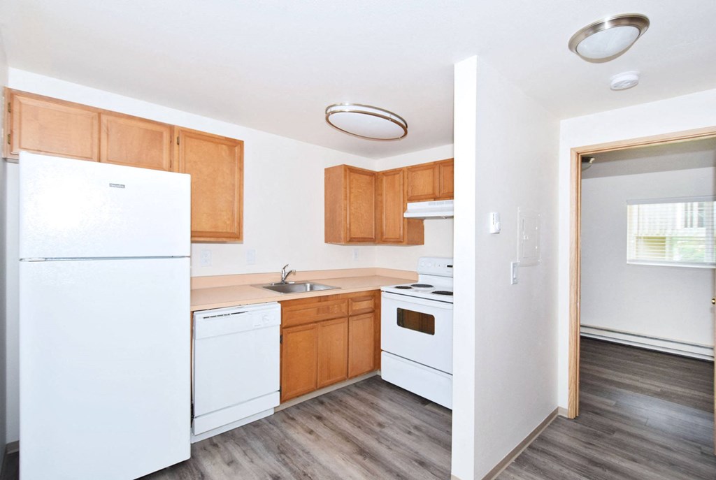 an empty kitchen with white appliances and wooden cabinets