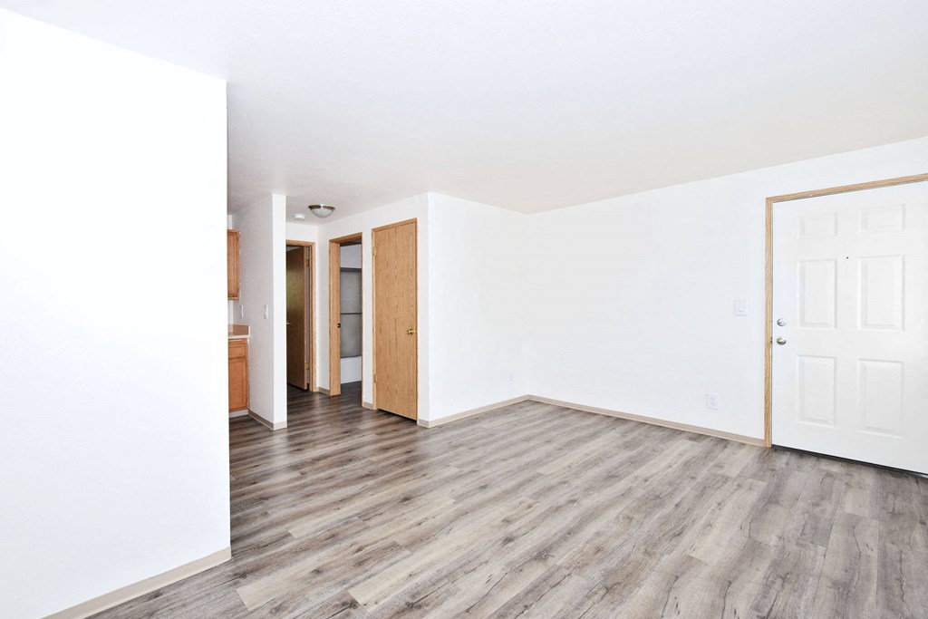 an empty living room with white walls and wood floors