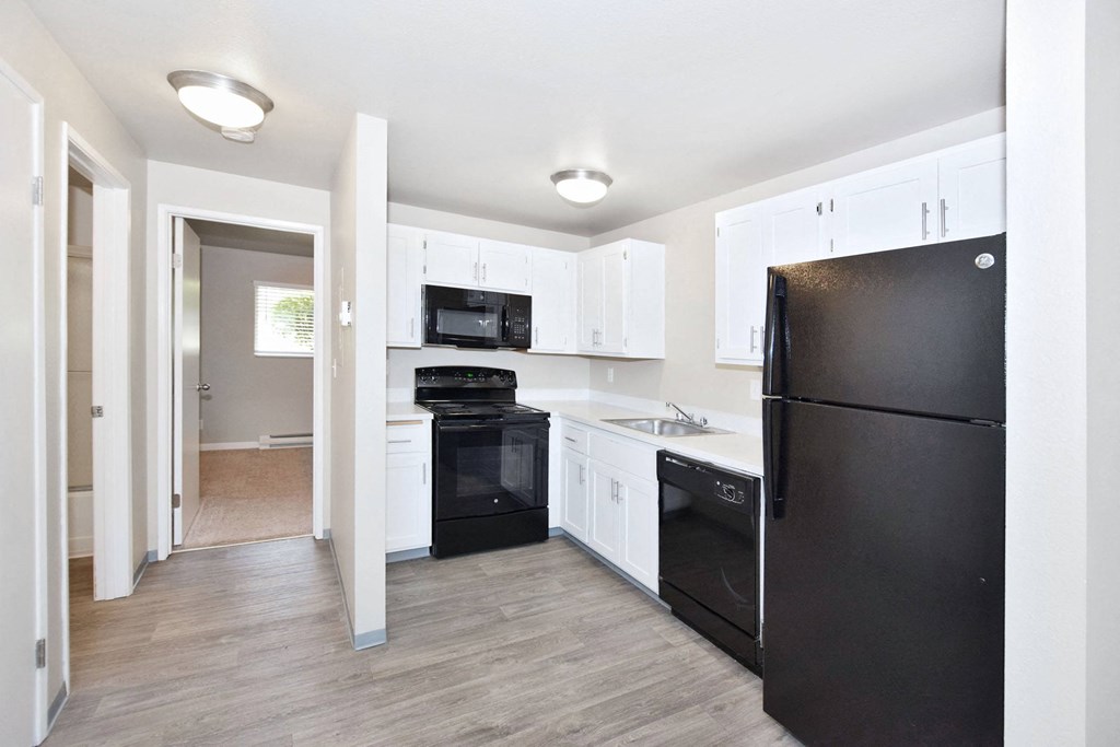 a renovated kitchen with black appliances and white cabinets