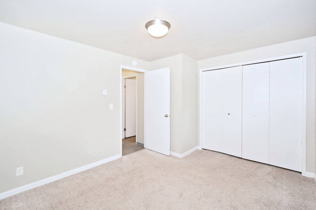 a bedroom with white walls and white closets and carpet