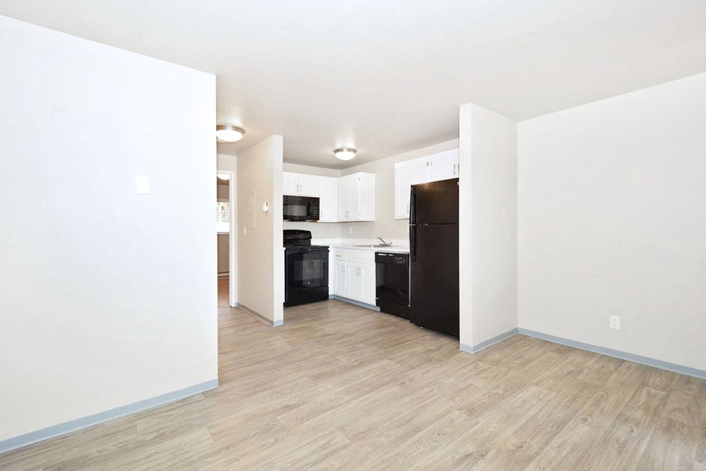 a renovated living room and kitchen with white walls and wood floors