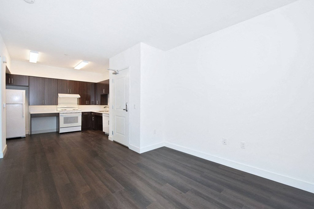 an empty living room and kitchen with white walls and wood floors
